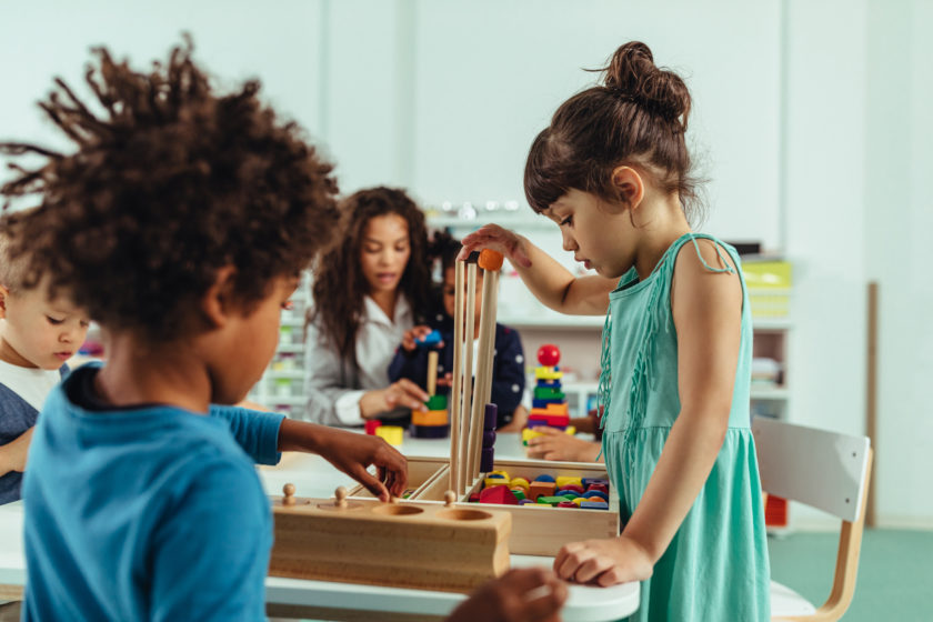 A group of children playing with wooden blocks in a classroom.